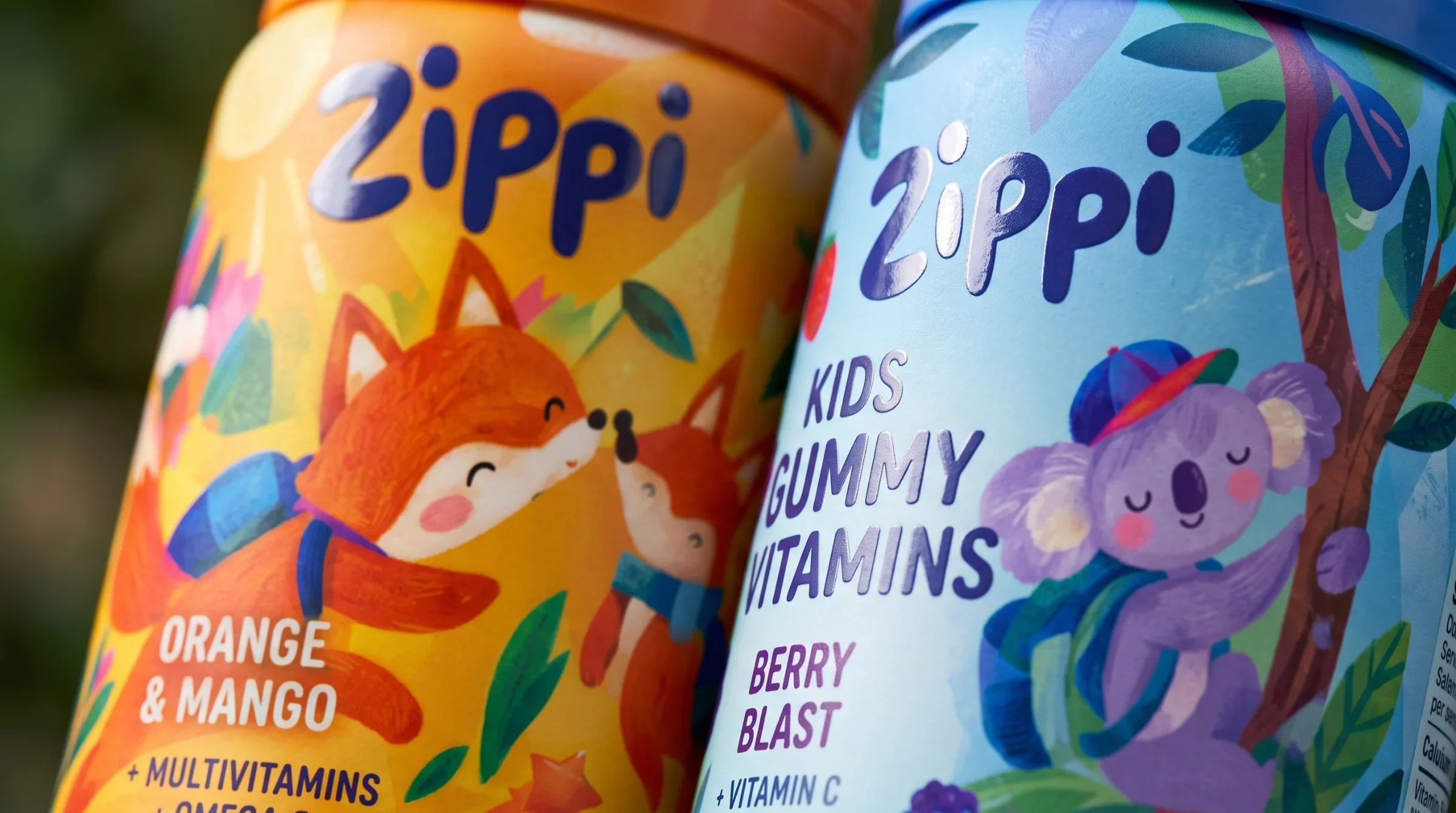 Close view of orange fox and blue koala bottle labels with the Zippi wordmark.